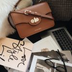 brown leather handbag beside macbook pro